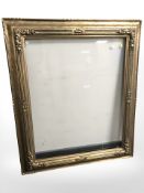 A gilt composition picture frame with inset pane of glass, inner measures 76 cm x 92 cm.