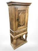 A continental oak single door cabinet on stand, 67 cm x 31 cm x 148 cm.