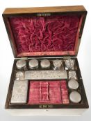 A Victorian rosewood vanity box containing assorted EPNS-lidded crystal jars, width 30 cm.