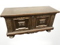 A continental carved and stained oak low sideboard, fitted cupboards beneath,