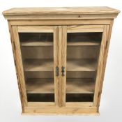 A glazed pine double door bookcase, 85 cm x 30 cm x 104 cm.