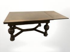 An early 20th century continental oak extending dining table on turned bulbous supports,