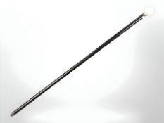 An ebonised walking cane with faux ivory pommel, length 93 cm.