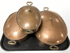 Three antique graduated hammered copper plated dishes and covers, largest 36 cm wide.