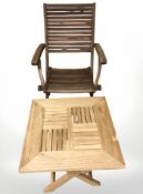 A teak folding garden table and similar armchair