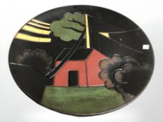 An Art Deco earthenware plate depicting a house amongst trees, diameter 31 cm.