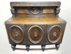 A 1920's heavily carved oak bow front sideboard, 152 cm x 61 cm x 142 cm.