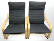 A pair of Ikea Poang bent and laminated wood armchairs with black fabric seats,