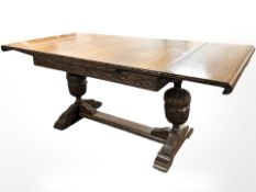 A 1920s carved oak pull-out extending refectory dining table on bulbous supports,