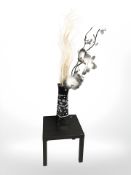 A modern vase containing artificial flowers and a square lamp table,