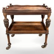 A 1920's heavily carved oak two tier serving trolley, length 80 cm.