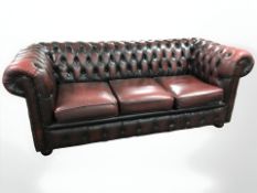 A Chesterfield buttoned oxblood leather three seater club settee, length 196 cm.
