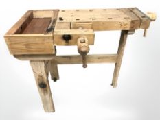 A small vintage pine work bench fitted with two vice,