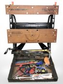 A folding Black and Decker work bench with a box of assorted hand tools