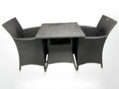A black woven plastic garden table and two armchairs