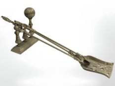 A pair of brass fire tongs, a shovel and a fire dog.