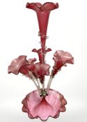 A Victorian cranberry glass epergne with seven tapering flower holders and clear glass stems,