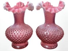 A pair of late Victorian textured cranberry glass flared rim vases, height 27 cm.