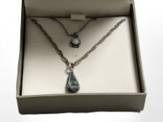 A silver necklace with small opal cabochon and a similar opal tear drop pendant on chain.