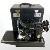 A Singer featherweight electric sewing machine with storage box.