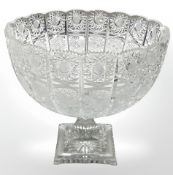 A large 19th century circular cut glass bowl with wavy rim, rasied on a faceted stem on square base,