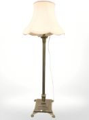 An ornate brass standard lamp on paw feet,
