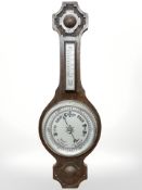 An early 20th century carved oak barometer with silvered dial, length 76 cm.