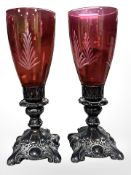 A pair of red glass vases standing on silver plated bases,
