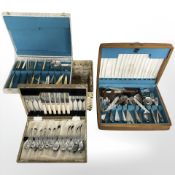 A wicker basket containing three cutlery canteens.