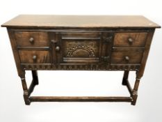 A 20th century carved oak side table, with cupboard and drawers,