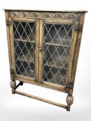 A 20th century carved oak double door side cabinet with leaded glass doors,