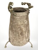 A rustic adzed wooden vase on brass tripod support with twin handles, height 65 cm.