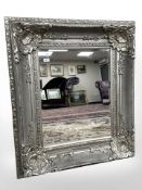 A contemporary bevelled mirror in an ornate silvered frame, 92 cm x 105 cm.