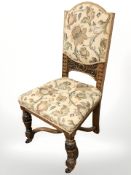 A heavily carved oak chair on x-framed under stretcher, in Arts and Crafts style fabric.