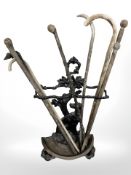 A Victorian painted cast iron stick stand containing rustic walking sticks