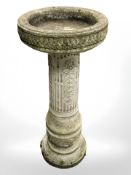 A weathered concrete circular pedestal bird bath,