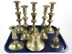 A group of brass candlesticks and two bells.