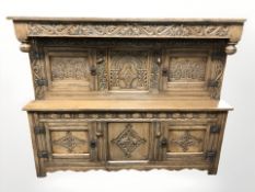 A 20th century heavily carved oak cupboard, 153 cm W x 47 cm D x 122 cm H.