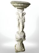 A weathered concrete garden bird bath held aloft by the Three Grace's,