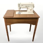 A Singer 507 electric sewing machine in teak table, width 72 cm.