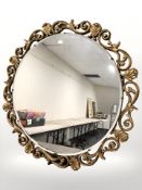 A decorative gilt and bevelled mirror, diameter 76 cm.