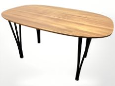 A teak oval table on metal hairpin legs, 135 cm x 85 cm x 70 cm.