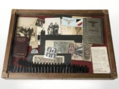 A counter top display cabinet containing German Third Reich items including stamps, photographs,