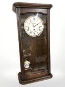 A mahogany wall clock, with pendulum, length 57 cm.