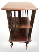 A reproduction mahogany revolving book table on castors, height 92 cm.