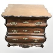 An early 19th century miniature mahogany three drawer serpentine front bombe commode,