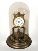 A brass anniversary timepiece under glass dome, with key, height 30 cm.