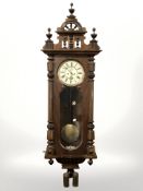 A walnut Vienna wall clock, with enameled dial, weights, pendulum and key, length 135 cm.