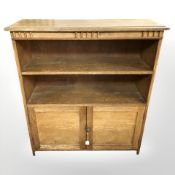 An early 20th century oak open bookcase with cupboards beneath,