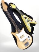 A homemade slim-bodied electric guitar and a child's flying V-shaped ukulele.